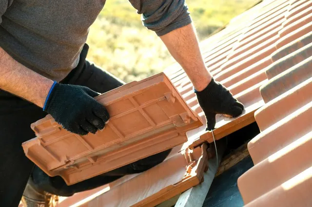 A Person Repairing A Damaged Roof Tile